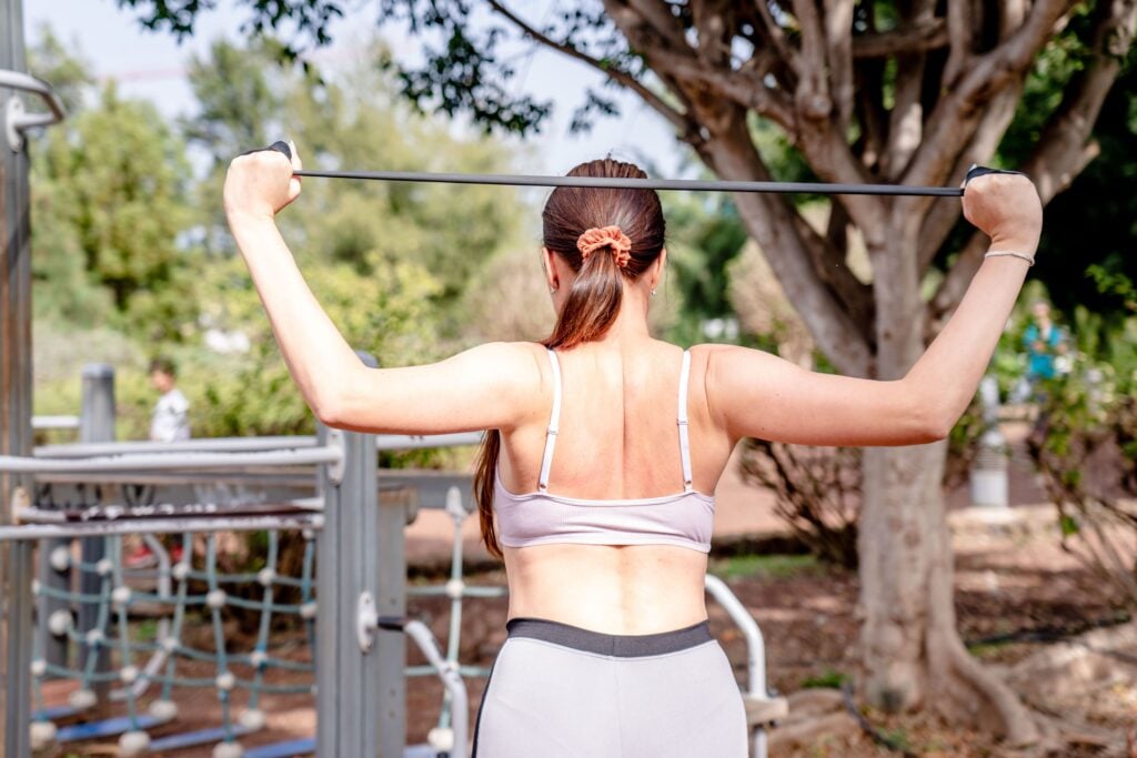 Woman using a resistance band for workout at an outdoor gym, showcasing healthy and active lifestyle.