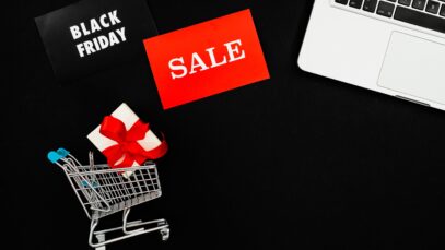 Top view of Black Friday sale with red gift box and laptop on black background.