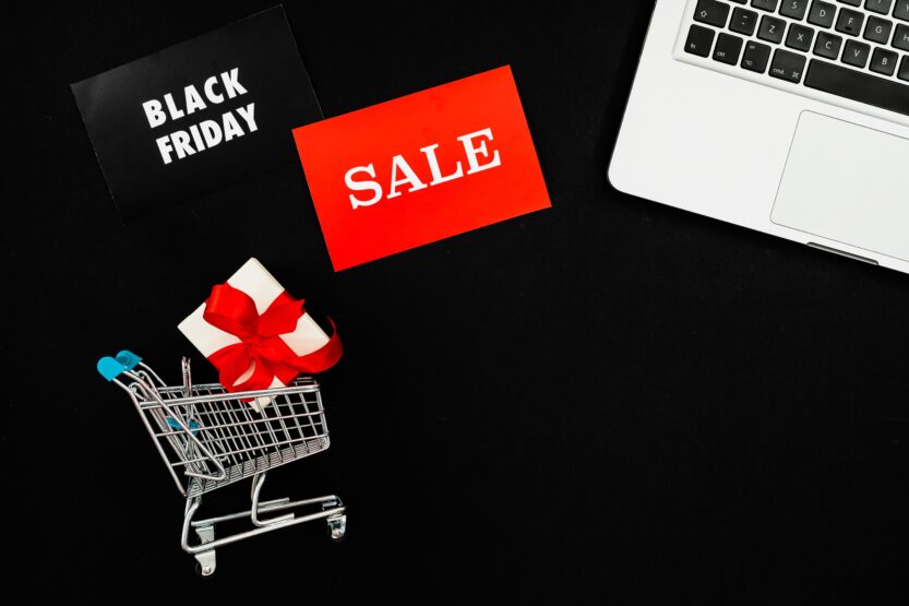 Top view of Black Friday sale with red gift box and laptop on black background.