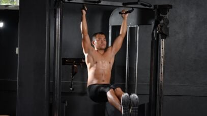 A shirtless man doing a workout with pull-up bar indoors at a gym, showcasing fitness and strength.