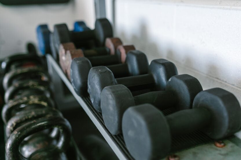 Neatly arranged dumbbells and kettlebells on racks in a gym environment.