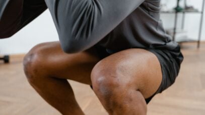 A focused view of a male athlete performing squats in a gym setting, emphasizing fitness and strength.