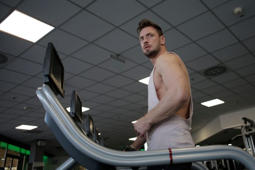 Gym Members Are Spending More Time In Sustainable Training Zones 1 Low angle of muscular adult male athlete in sportswear during training on running machine in modern spacious fitness center while looking away