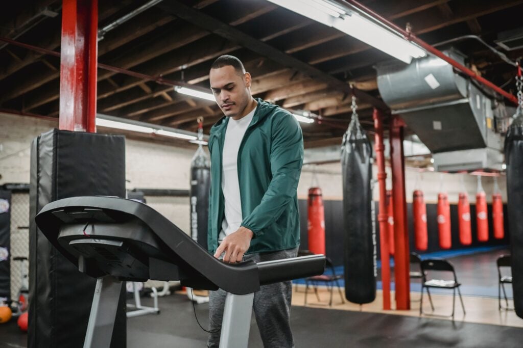 Gym Members Are Spending More Time In Sustainable Training Zones 14 Serious sporty male in sportswear pressing buttons on treadmill while training in contemporary gym
